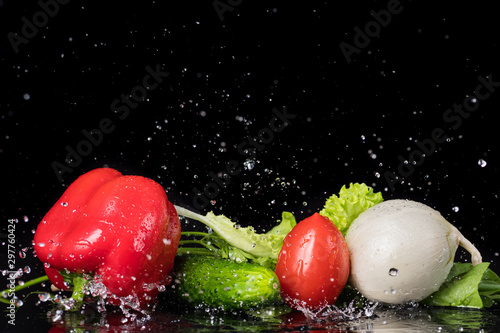 fresh vegetables with drops of water on a black background, pidor, cucumber, bell pepper, onion, greens photo