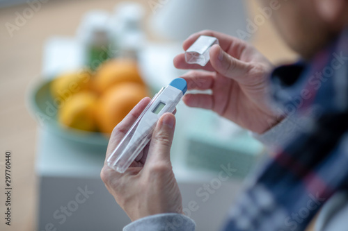 Man using thermometer while having high fever