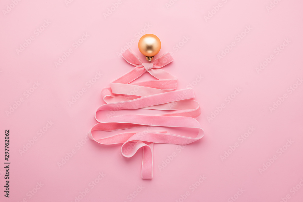 Christmas creative tree made of ribbon decorated with golden ball a pastel pink background. Festive minimalism concept. - obrazy, fototapety, plakaty 