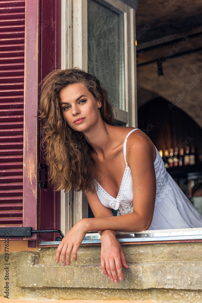 Fototapeta premium Portrait of laughing young woman looking through window of a cafe.