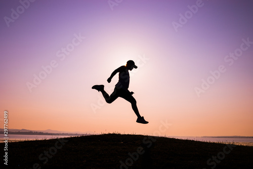 The silhouette of Asian men trail running, the sky at sunrise running in the mountains, lifestyle