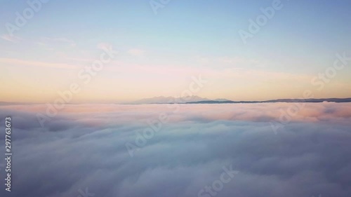 Aerial footage of beautiful morning landscape covered with low clouds. Morning view above clouds with High Tatras in distance.