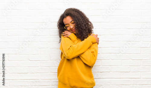 Vászonkép young black woman feeling in love, smiling, cuddling and hugging self, staying s