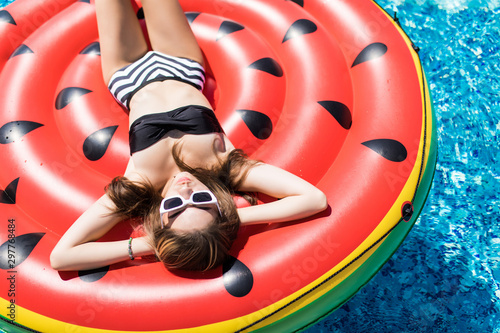Young and sexy girl having fun and laughing on an inflatable giant watermelon pool float mattress in a bikini. © F8  \ Suport Ukraine