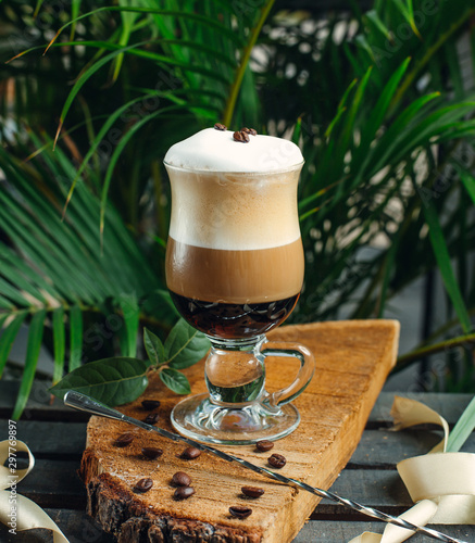 layered coffee with cream and coffee beans on rustic wood board photo