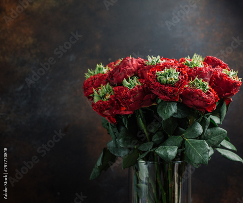 bouquet of red flowers in glass vase in dark background