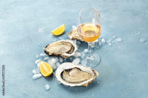 Tableau sur toile Fresh raw oysters on ice with a glass of white wine and lemon slices, with copy