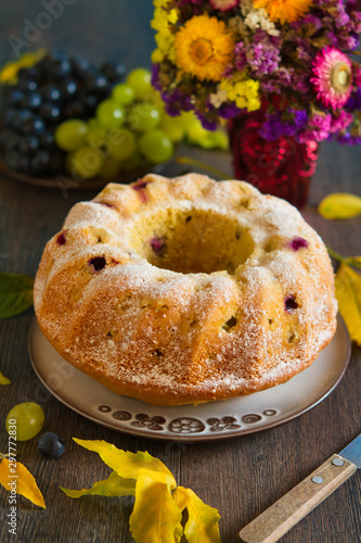 Homemade bundtcake with autumn grapes on a table with fall decoration photo