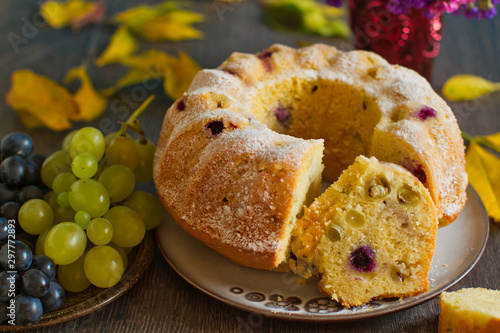 Homemade bundtcake with autumn grapes on a table with fall decoration photo