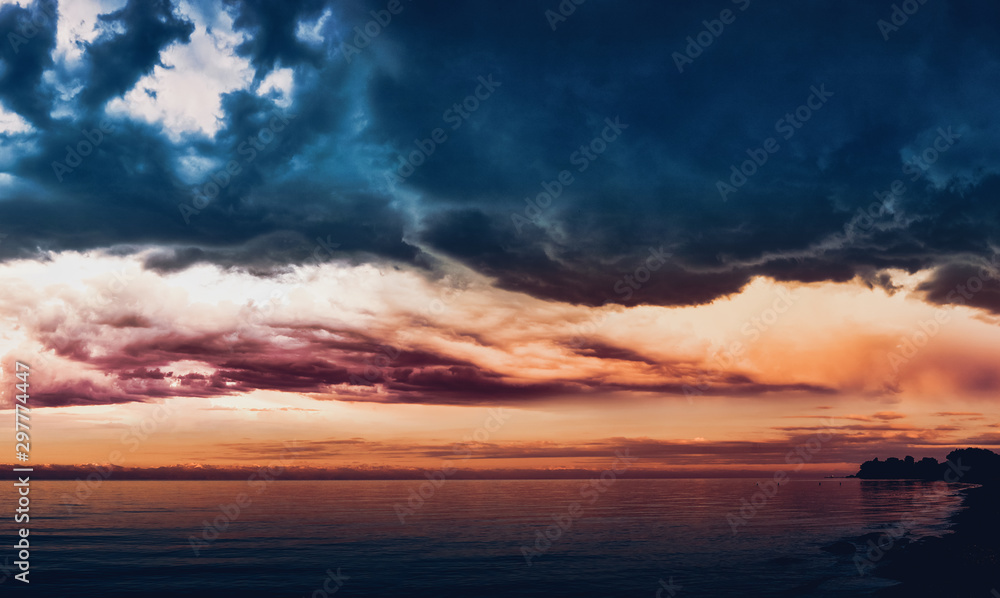 Dramatic light through the clouds against the backdrop of an exciting, stormy stormy sky at sunset, dawn. Hatching in water panorama, natural composition