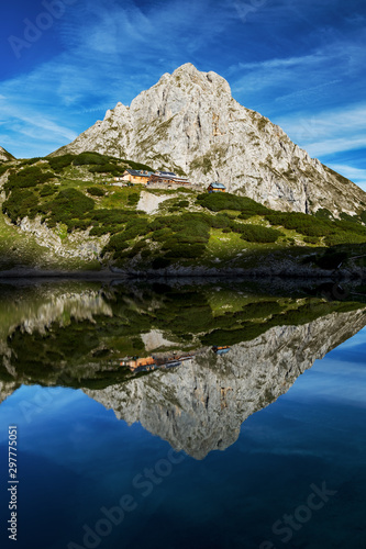 Sonnenspitze with coburger hut reflecting in the lake drachensee. Austria alps near leermos