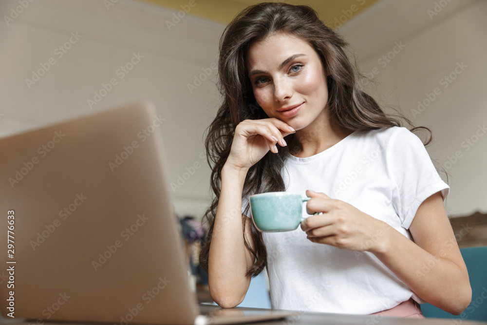 Happy young woman indoors at home using laptop Happy young woman indoors at home using laptop