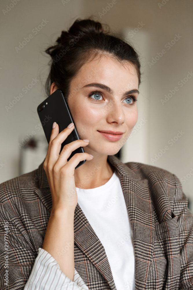 Business woman indoors at home talking by mobile phone. Business woman indoors at home talking by mobile phone.