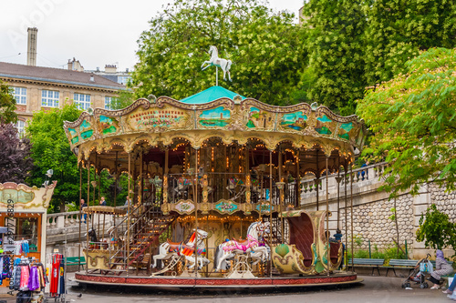A lovely French old-fashioned style carousel with rows of wooden horses mounted on posts and a staircase to the second floor in the Louise Michel Square at the base of the butte Montmartre in Paris.