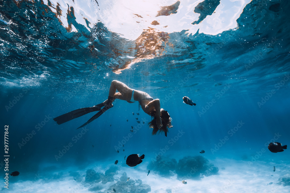 Woman freediver with fins relaxing underwater. Freediving and beautiful light in ocean