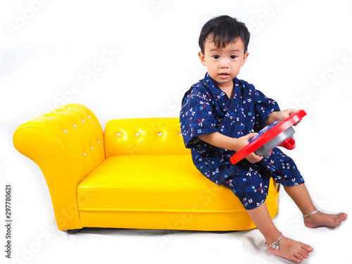asian little boy Wearing yukata sit on yellow sofa  on white backgound