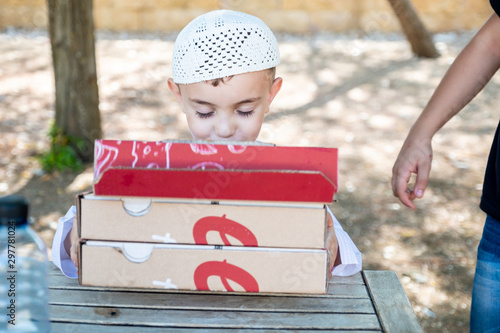 Happy arabic boys enjoying pizza together at the park photo