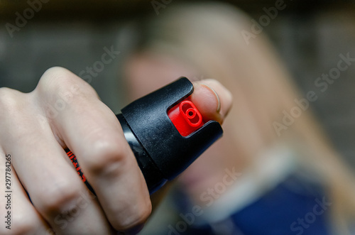 Blonde woman holding pepper spray for self defense close up