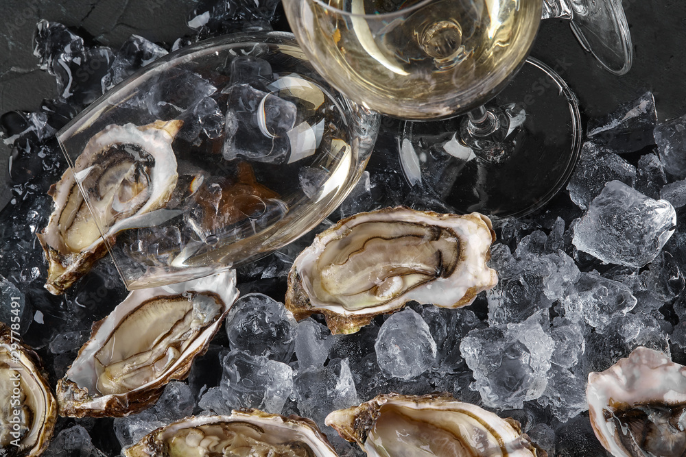 Fresh opened oysters in ice on a black stone textured background. Top view. Close-up shot. Fresh opened oysters in ice on a black stone textured background. Top view. Close-up shot.