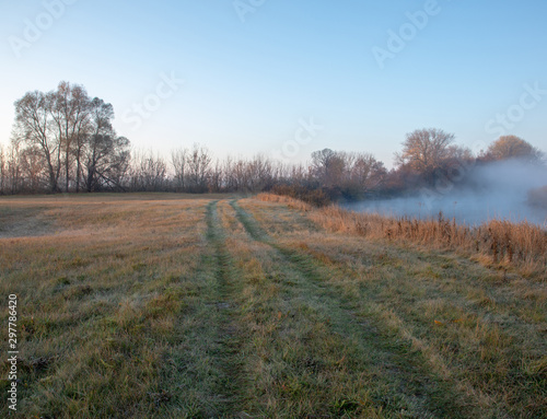 Morning fog over the autumn river in the early morning, frost on the grass.