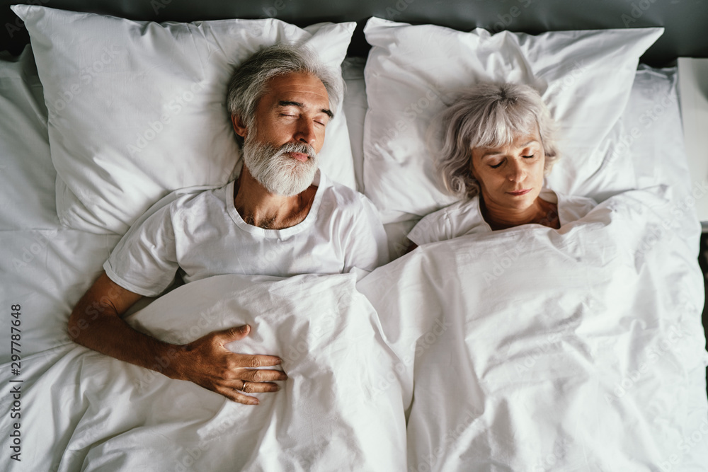 Senior family couple sleeping together in bed. - obrazy, fototapety, plakaty 