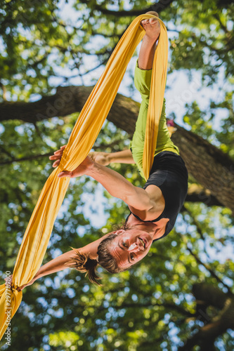 Aerial silk artist performing in sunny nature.