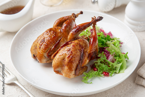 Whole roasted quail on white plate