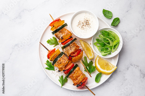 Grilled salmon and vegetables skewers on white plate