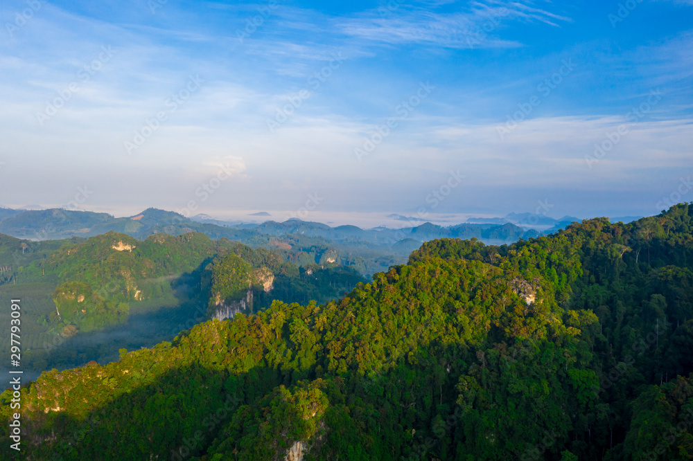 Fototapeta premium Aerial view of mountains with cloud cover mountain at sunrise and blue sky in Surat Thani Province, Thailand.