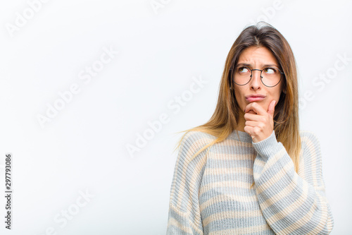 young pretty woman thinking, feeling doubtful and confused, with different options, wondering which decision to make against white background photo