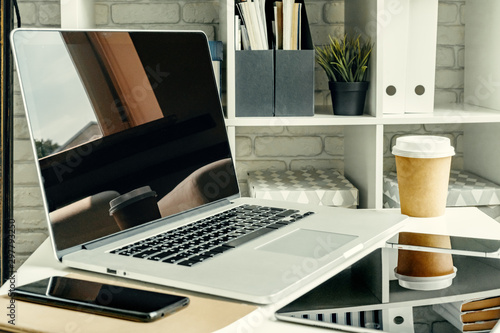 Laptop in a light room on working table with office supplies