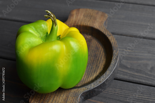 Organic green pepper in wooden plate on dark wooden table background  top view  copy space