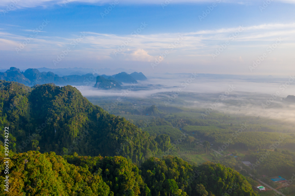 Naklejka premium Aerial view of mountains with cloud cover mountain at sunrise and blue sky in Surat Thani Province, Thailand.