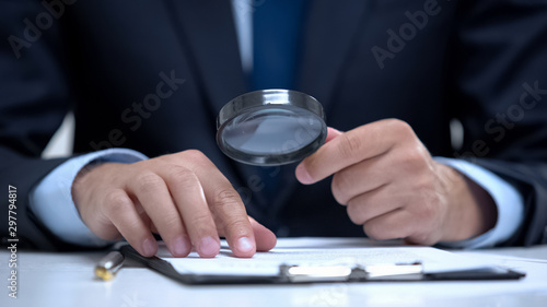 Obraz na płótnie Attorney reading document with magnifier, studying case in detail, investigation