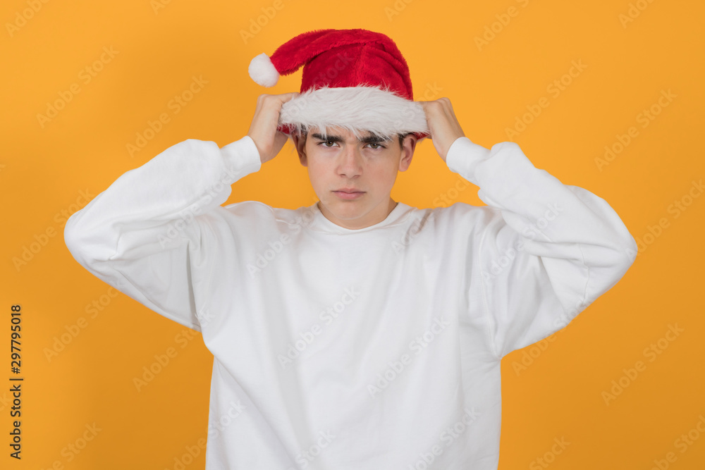 young teenage man with santa claus hat isolated on color background young teenage man with santa claus hat isolated on color background
