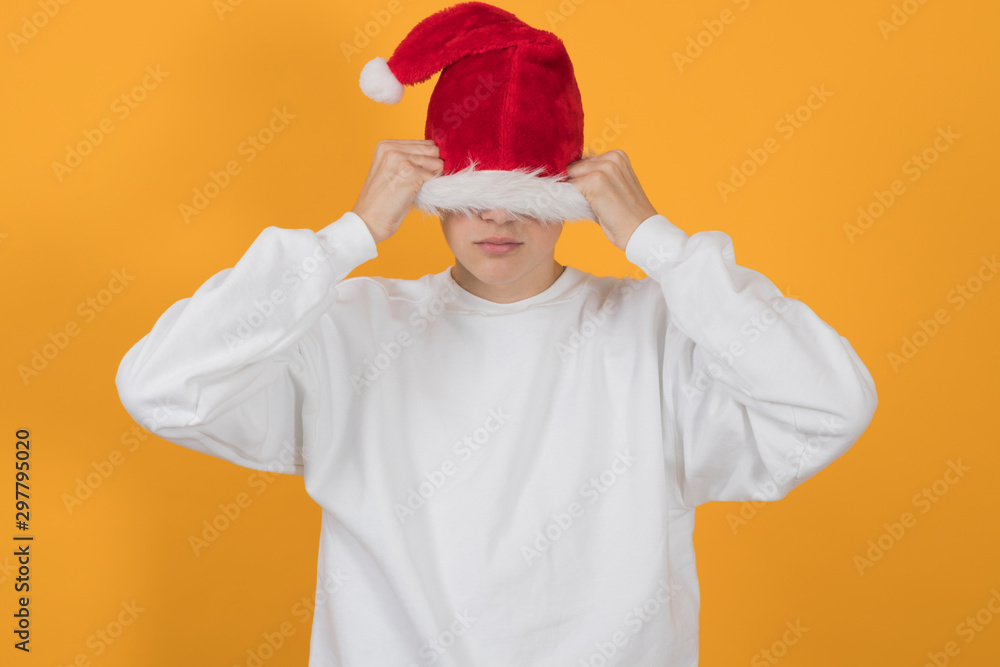 young teenage man with santa claus hat isolated on color background young teenage man with santa claus hat isolated on color background