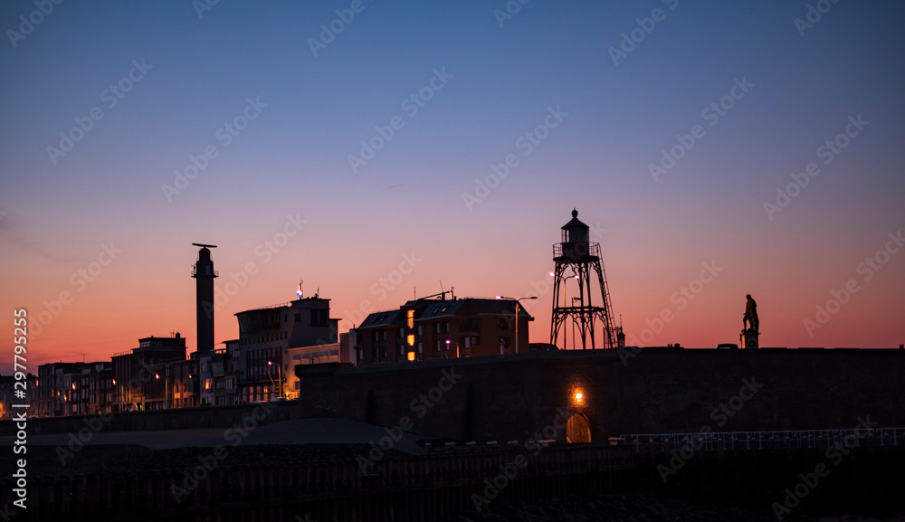 skyline of vlissingen with lighthouse and the statue of willem de ruyter in the evening colors