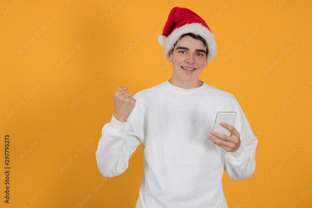 young teenage man with santa claus hat isolated on color background young teenage man with santa claus hat isolated on color background