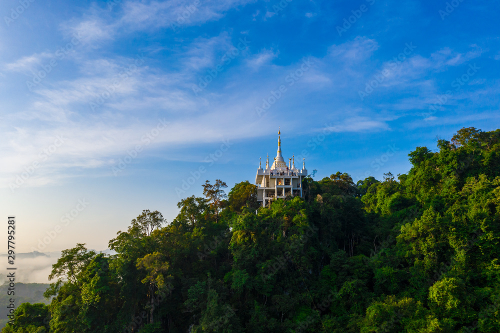 Aerial scenery of white pagoda on the mountain with cloud at sunrise in the morning in Surat Thani province, Thailand
