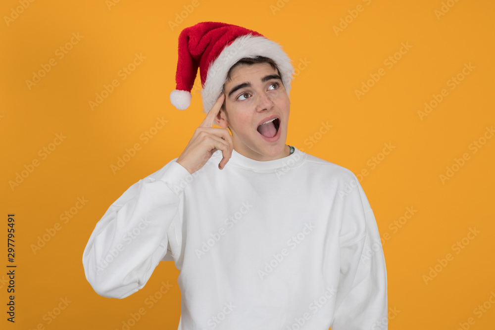 young teenage man with santa claus hat isolated on color background young teenage man with santa claus hat isolated on color background
