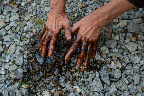 Caucasian hands stained with black gasoline on stones background photo