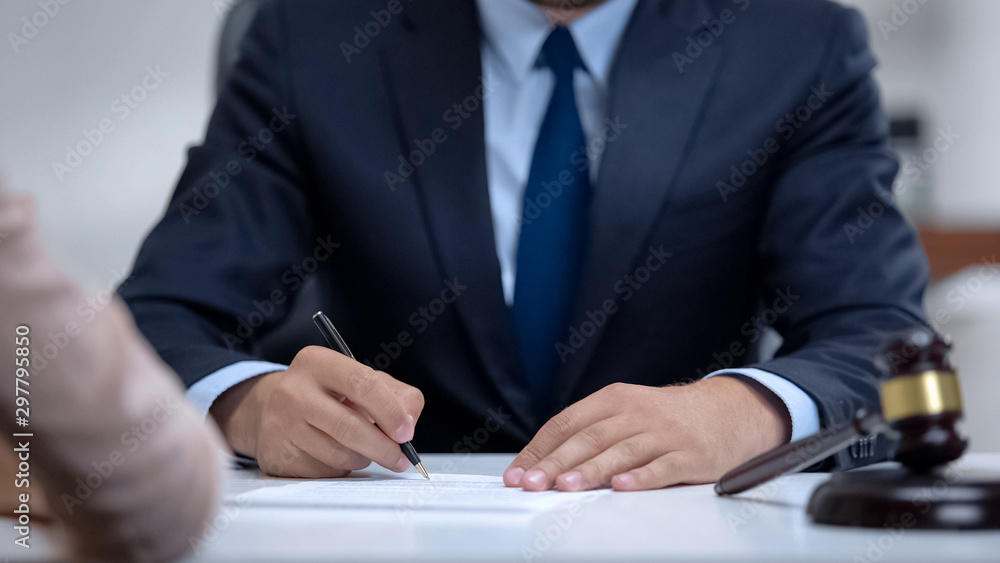 Male lawyer writing down clients testimony to make legal case, close-up Male lawyer writing down clients testimony to make legal case, close-up