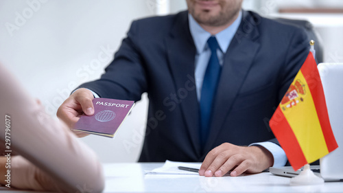 Spain consular officer giving passport to immigrant, work visa, citizenship photo