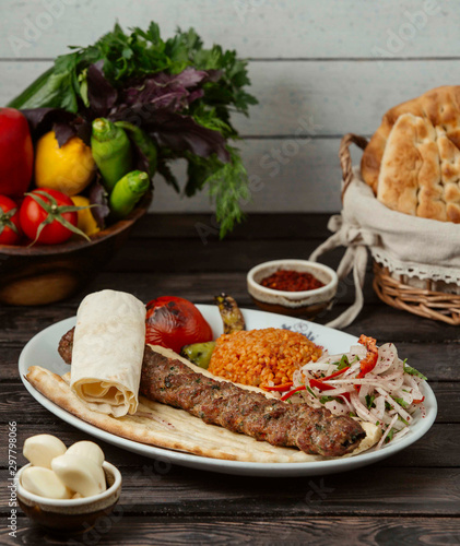 adana kebab on pita bread served with bulgur and onion slices photo