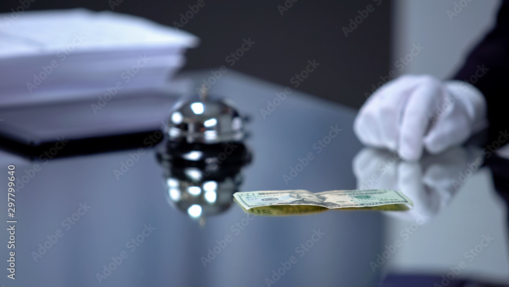 Dollar banknote lying front hotel receptionist, bribe for revealing secrets Dollar banknote lying front hotel receptionist, bribe for revealing secrets