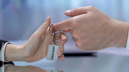 Vacant word written on keychain female taking from male boss hand, employment