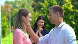 Cheerful man and woman smiling each other, happy friend on background, love