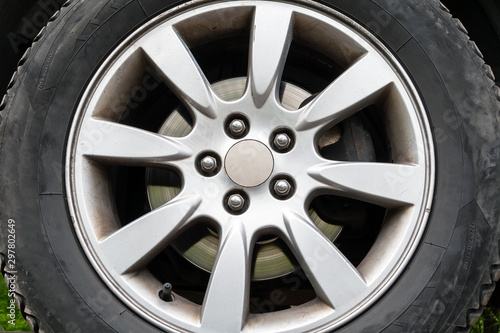 A closeup view of a car wheel with winter tires, silver brake disc and a five-nut rim