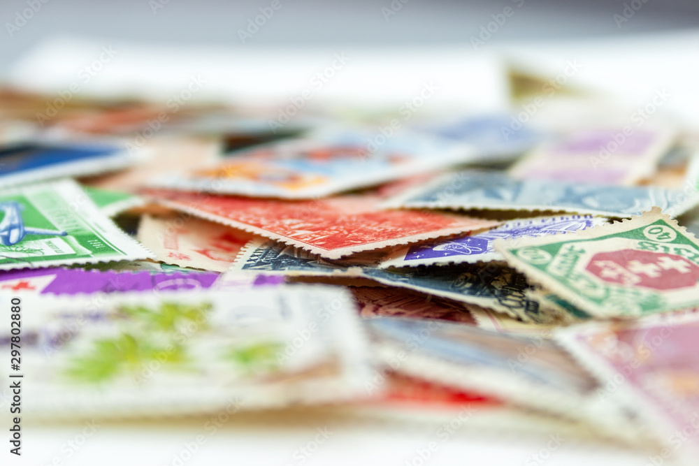 Closeup view on a variety of multi-colored postage stamps from different countries and years. Selective focus Closeup view on a variety of multi-colored postage stamps from different countries and years. Selective focus