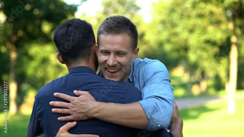 Two male friends hugging outdoors, pleasure emotions, friendship happiness